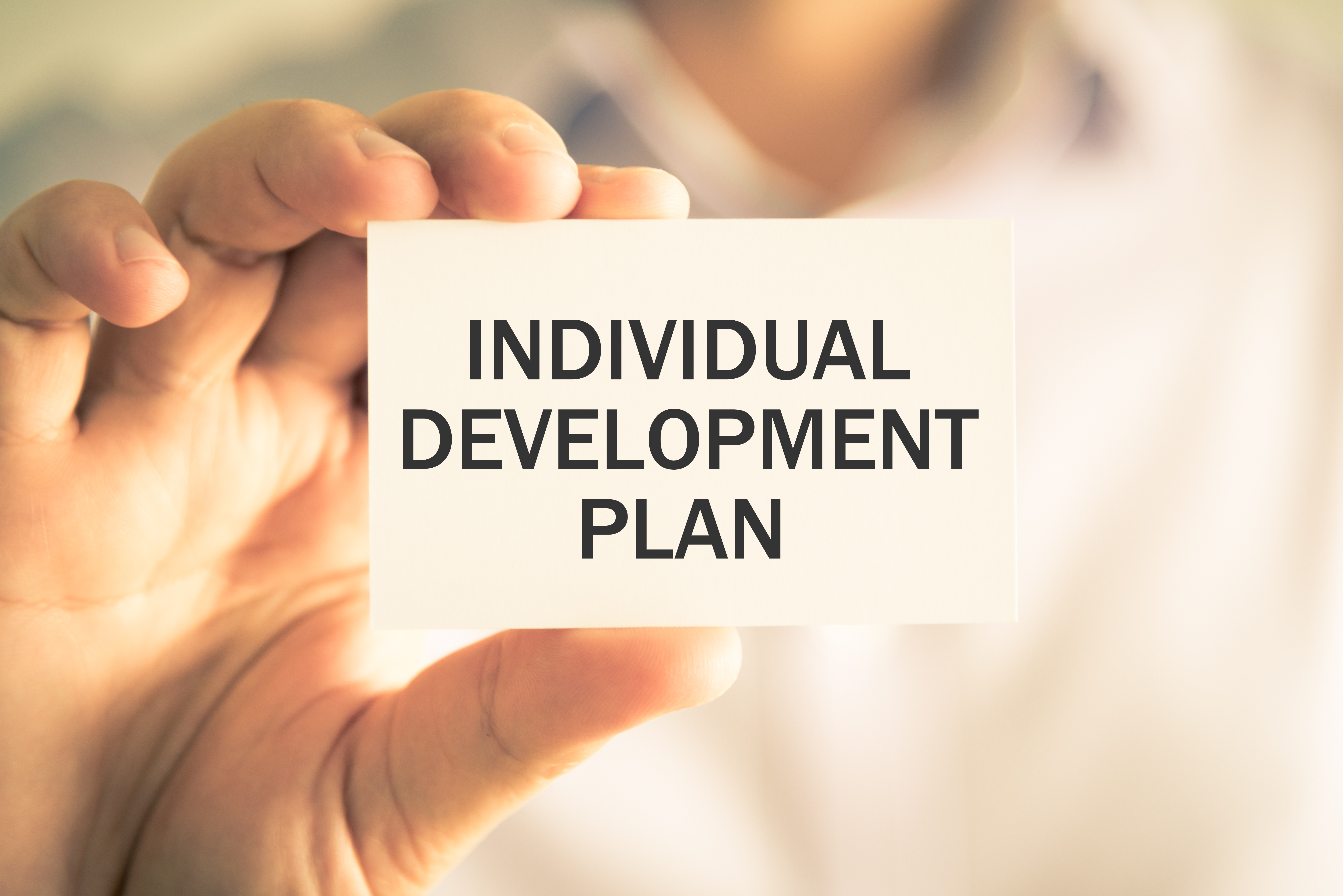 individual development plan written on small tiny paper held by a person